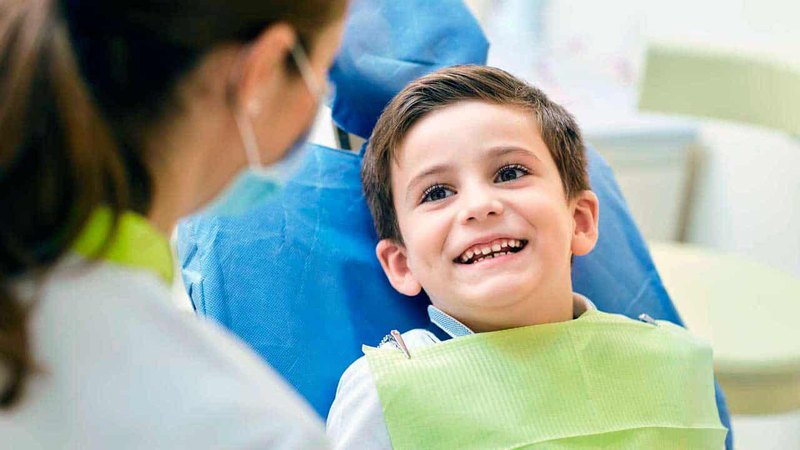A smiling child in the midst of a children's pediatric dentistry checkup with a dentist