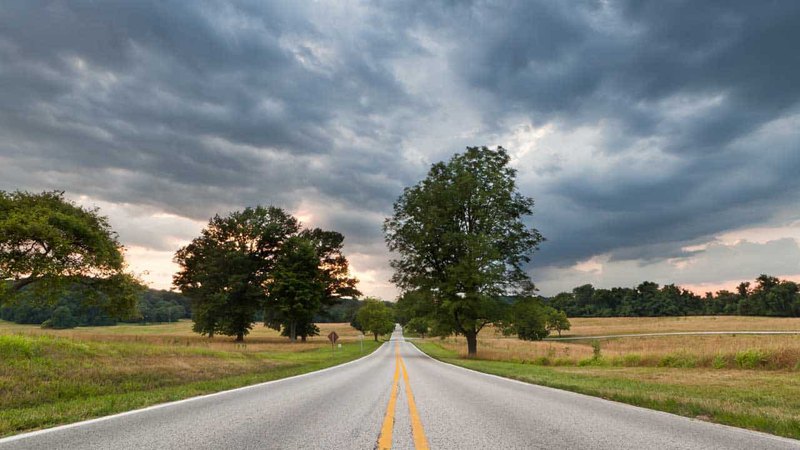 Beautiful road passing through a field during stormy weather leading to dental center near Rosemont